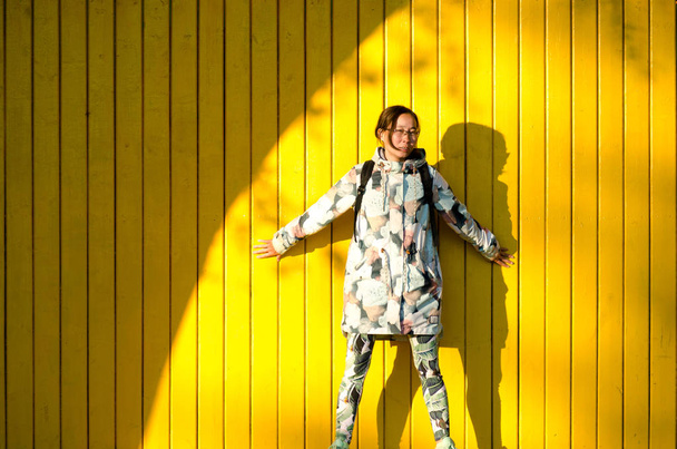 Piękny Yakut model młodej dziewczyny seksualnie wciśnięty jej ręce do żółtego drewnianej ścianie w jasnym słońcu obok półkole cień. - Zdjęcie, obraz
