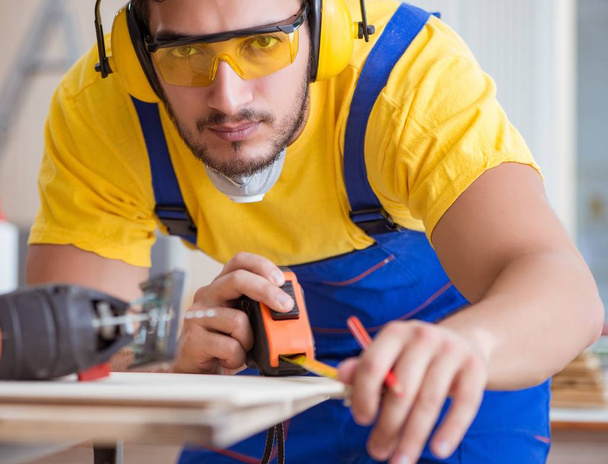 carpintero joven reparador que trabaja cortando madera en sierra circular - Foto, Imagen