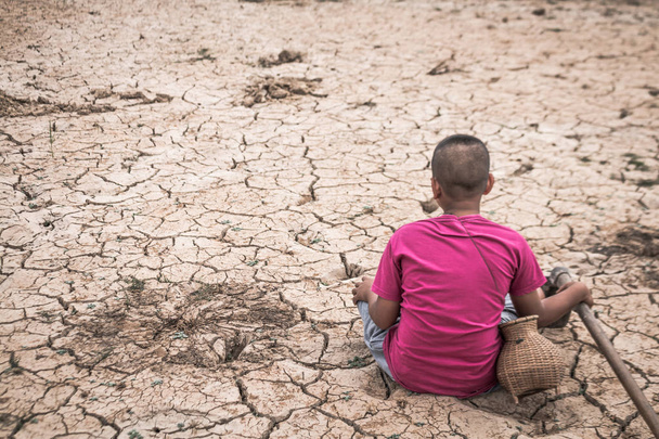 El niño se sentó en un suelo estéril con desesperación, concepto de sequía y
 - Foto, imagen