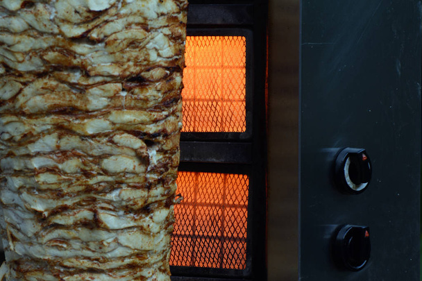 Fleischstücke auf einer Metallstange neben einem beheizten Elektroofen aufgereiht. Shawarma kochen in der Türkei - Foto, Bild