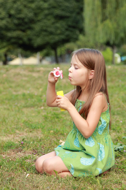 Cute little girl is blowing a soap bubble - Foto, afbeelding