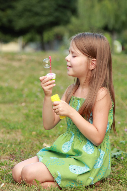 Little girl playing in the park with soap bubbles - Foto, imagen