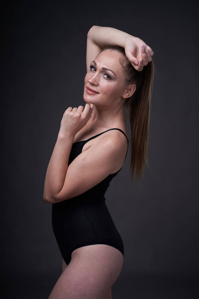 flexible sexy girl poses on a black grey background in the fitting clothes baud - Foto, Bild