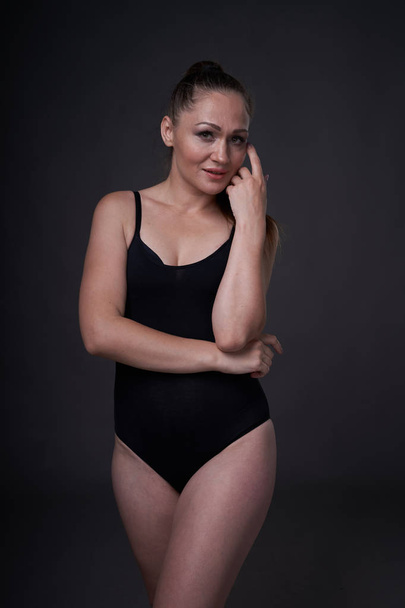 flexible sexy girl poses on a black grey background in the fitting clothes baud - Fotó, kép