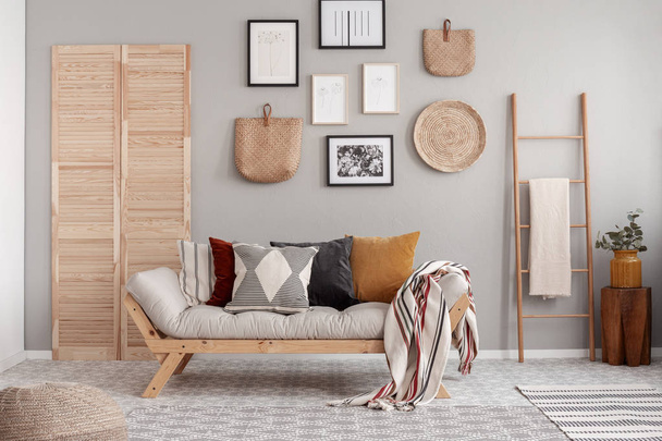 Wooden and wicker accessories in fashionable scandinavian living room interior with futon sofa with pillows - Φωτογραφία, εικόνα