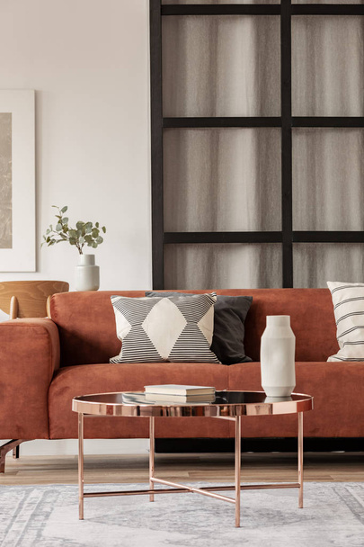 Stylish brown corner sofa with patterned pillows in elegant living room interior with mullions wall - 写真・画像