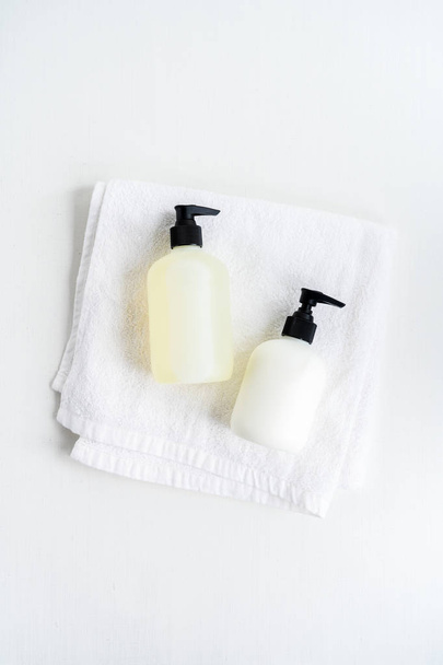 Paar flessen liggend op witte pluizige handdoek over witte achtergrond - Foto, afbeelding
