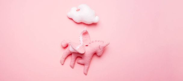 Felt toy unicorn from baby mobile with cloud on pink background.  - Photo, Image