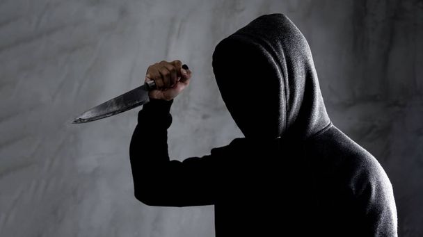 Niebezpieczny człowiek z kapturem stojący w ciemności i posiadający nóż FA - Zdjęcie, obraz