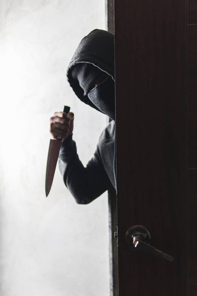 O ladrão segura uma faca para abrir a porta da casa por roubo. - Foto, Imagem
