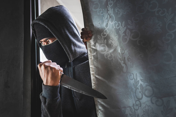 Ο κλέφτης κρατάει μαχαίρι για να ανοίξει την πόρτα του σπιτιού για ληστεία.. - Φωτογραφία, εικόνα