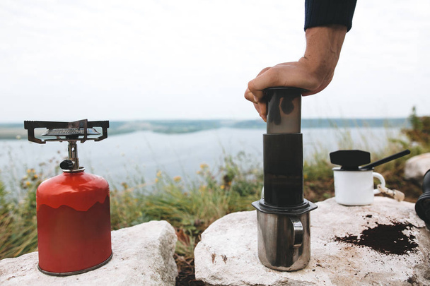 Voyageur pressant l'eau chaude à travers le café dans l'aération sur la falaise
 - Photo, image