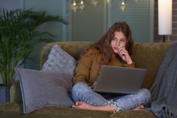 Προνοητικός έφηβος κορίτσι με φορητό υπολογιστή στον καναπέ τη νύχτα - Φωτογραφία, εικόνα