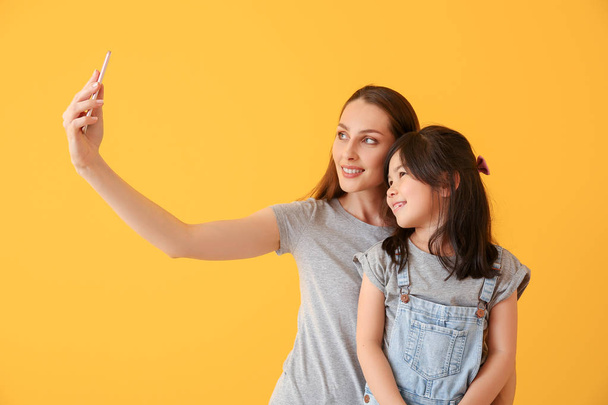 Happy mother with daughter taking selfie on color background - Foto, immagini