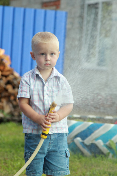 Little blond boy watering the lawn - Valokuva, kuva