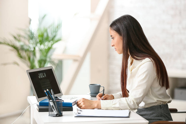 Женщина использует календарь на экране ноутбука во время работы в офисе
 - Фото, изображение
