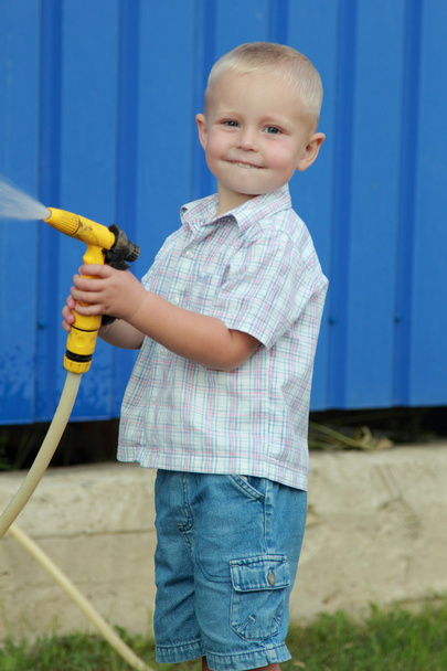 Little blond boy watering the lawn - Foto, Bild