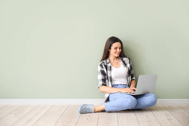 Female blogger with laptop sitting near color wall - Zdjęcie, obraz