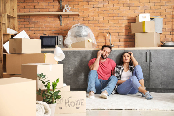 Tired couple sitting on floor after moving into new house - Photo, Image