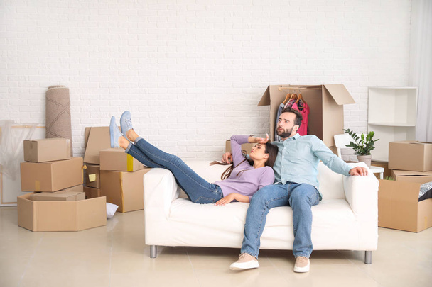 Jeune couple reposant sur un canapé après avoir emménagé dans une nouvelle maison
 - Photo, image