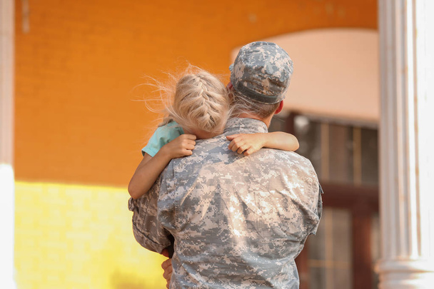 Sotilas halaa tytärtään ulkona.
 - Valokuva, kuva