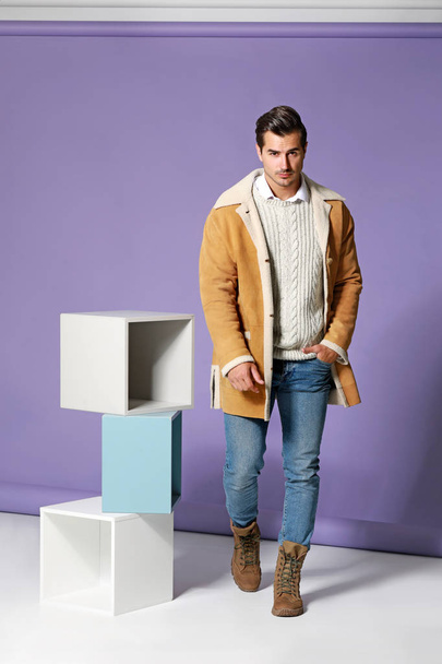 Fashionable man in warm clothes on color background - Фото, зображення