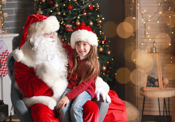 サンタクロースとクリスマスのために飾られた部屋の小さな女の子 - 写真・画像