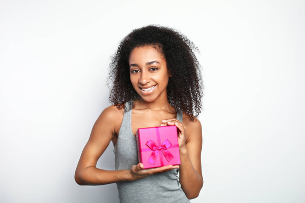 Πορτρέτο της όμορφης Αφροαμερικανικής γυναίκας με κουτί δώρου σε λευκό φόντο - Φωτογραφία, εικόνα