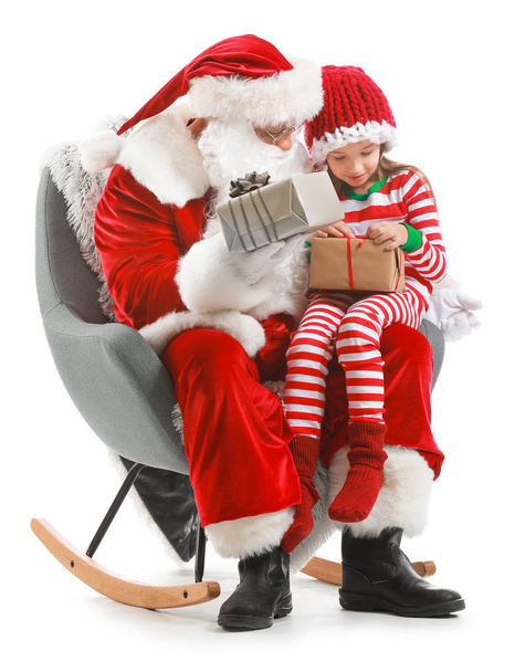 Père Noël et petite fille avec des cadeaux assis dans le fauteuil sur fond blanc
 - Photo, image