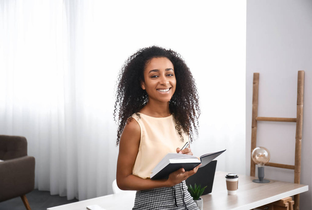 Portrait of beautiful African-American businesswoman with notebook in office - Foto, immagini
