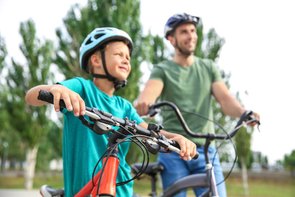 Gelukkige vader en zoon rijden fietsen buitenshuis - Foto, afbeelding