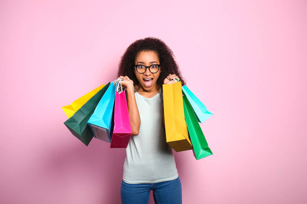Portrait of excited African-American woman with shopping bags on color background - Foto, Imagen