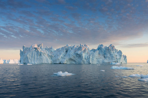 Natuur en landschappen van Groenland of Antarctica. Reis op het schip tussen ijs. Studeren van een fenomeen van aardopwarming Ices en ijsbergen van ongewone vormen en kleuren Prachtige middernachtzon op schip  - Foto, afbeelding