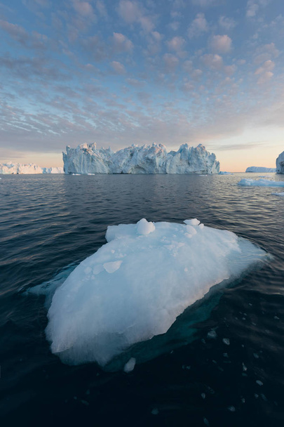 Grönland ya da Antarktika 'nın doğa ve manzaraları. Gemide buzların arasında seyahat et. Küresel ısınma fenomeni üzerinde çalışmak alışılmadık formlar ve renkler içeren buzdağları gemide güzel bir gece yarısı güneşi  - Fotoğraf, Görsel