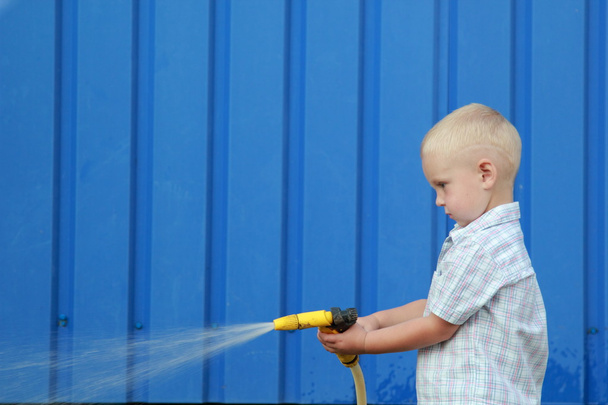 Little blond boy watering the lawn - Foto, immagini