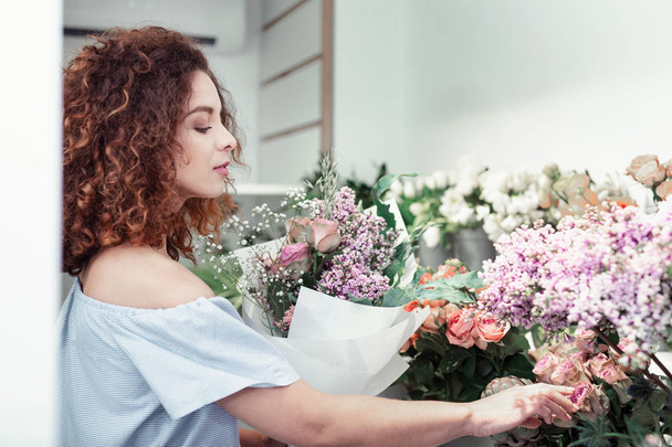 Özenli kısa saçlı kadın onun depolama sunulan çiçekler gözlemleyerek - Fotoğraf, Görsel