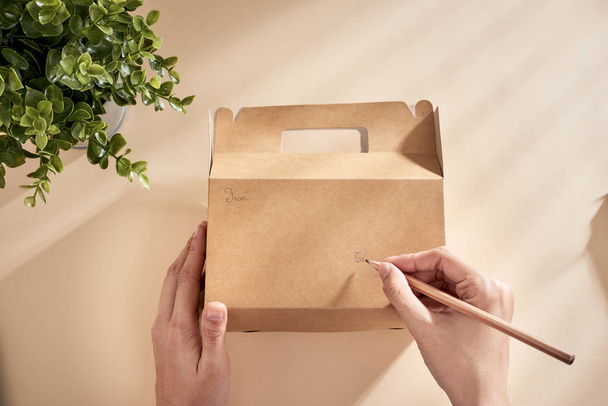 Обрізане зображення жінки, що пише найкращі побажання на коробці з подарунком
 - Фото, зображення