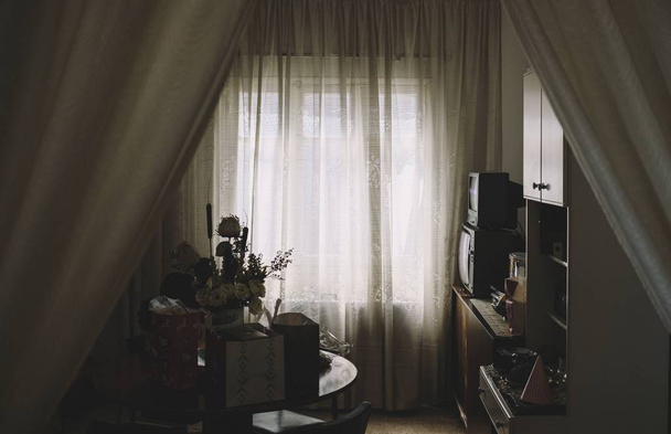 Shot of a cabinet, TVs, curtain near a table with a vase of flowers on it in a room - Φωτογραφία, εικόνα