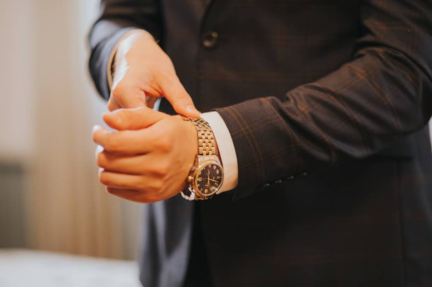 Primo piano della mano di un maschio che indossa il suo orologio classico prima dell'inizio della cerimonia nuziale
 - Foto, immagini