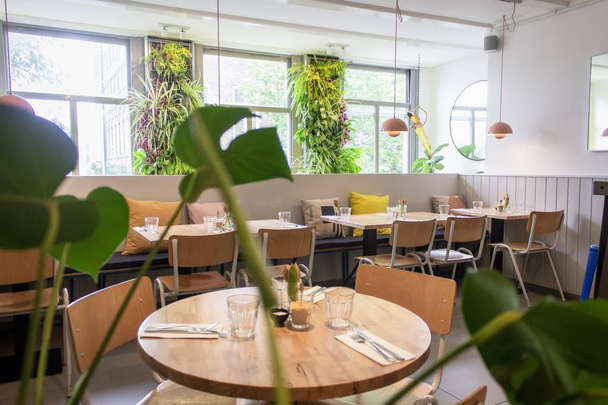 Selective focus shot of a restaurant with wooden tables and plants - Foto, afbeelding