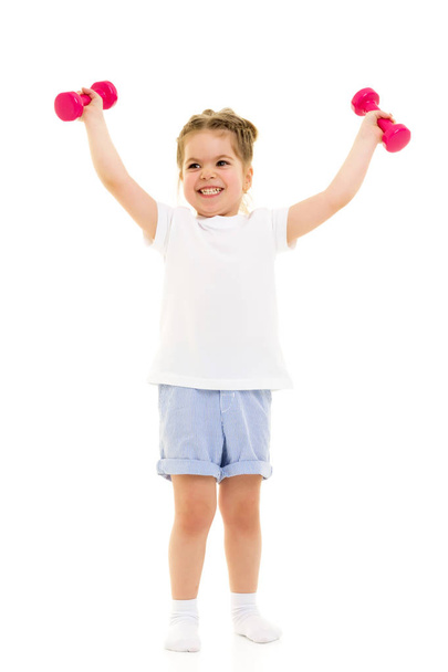 Little girl doing exercises with dumbbells. - Foto, Bild