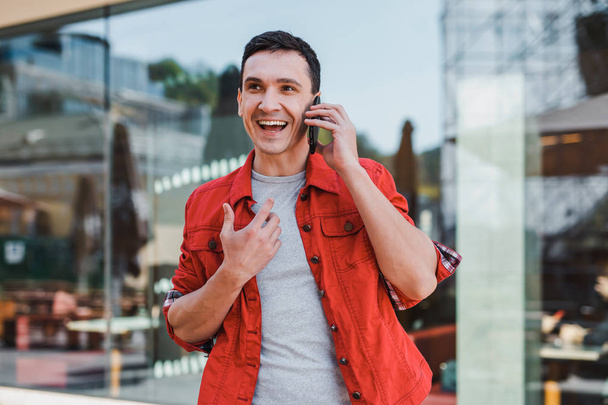 電話での会話を持つ赤いジャケットを着た感情的な男 - 写真・画像