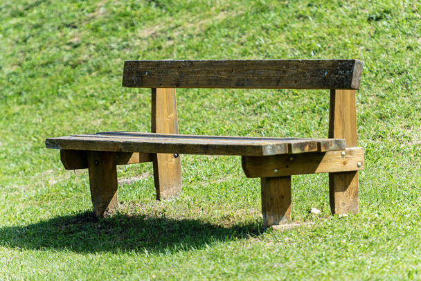Άδειο ρουστίκ ξύλινο παγκάκι σε ένα δημόσιο πάρκο - Φωτογραφία, εικόνα