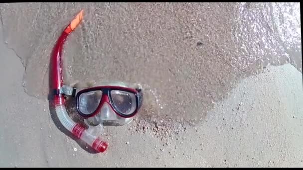 Maska z Snorkel leży na piaszczystym brzegu i rolkach fali surfowania na nim w słoneczny dzień. Ruch w zwolnionym tempie standardowy. - Materiał filmowy, wideo