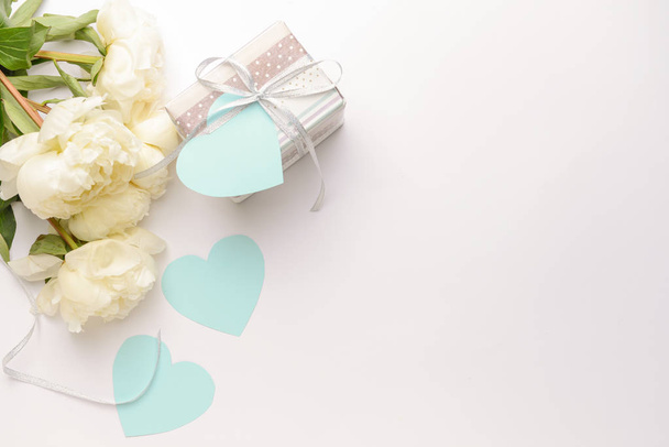 Gift box, paper hearts and beautiful flowers on light background - Фото, зображення