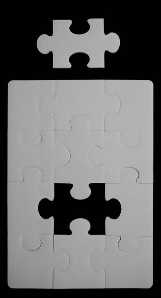 missing part. white  jigsaw with space and one of the missing pieces in the center - pieces fitting together  - Foto, imagen