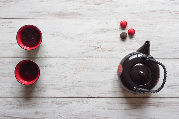 木製のテーブルの上の赤いカップティーと紅茶ポット - 写真・画像