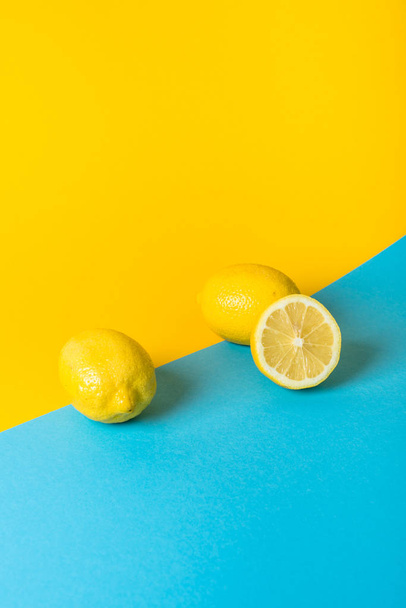 Natural fresh juicy lemons on yellow and blue background - Φωτογραφία, εικόνα