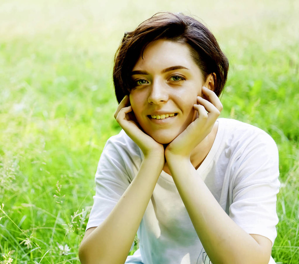 Beautiful portrait of pensive young short haired girl on blurred green grass meadow background, closeup.  - Φωτογραφία, εικόνα