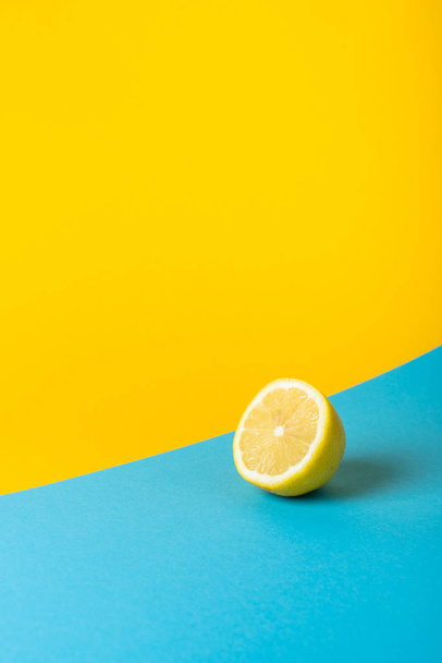 Природные свежие сочные лимоны на желтом и синем фоне
 - Фото, изображение